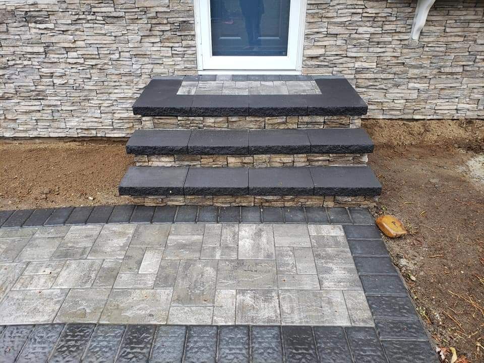 Stone steps and paved walkway leading to a front door with stone veneer exterior.