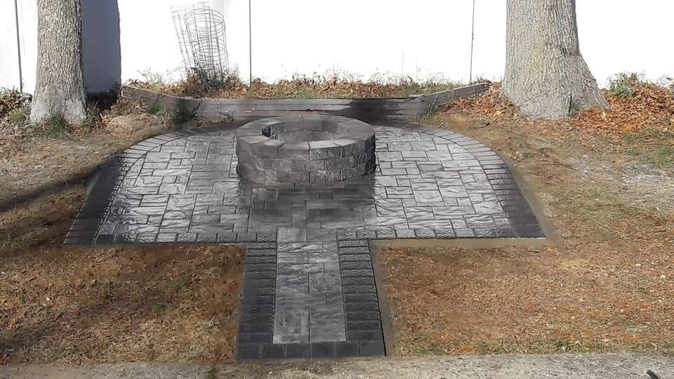 A stone patio with a fire pit in the middle of it.