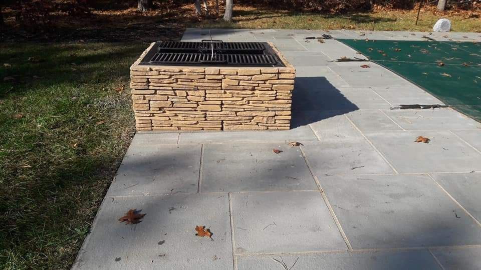 A fire pit is sitting on a patio next to a pool.