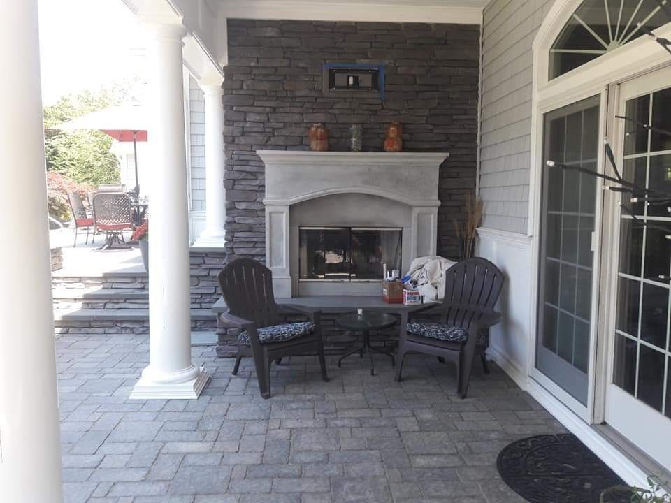 A patio with a fireplace and chairs on it