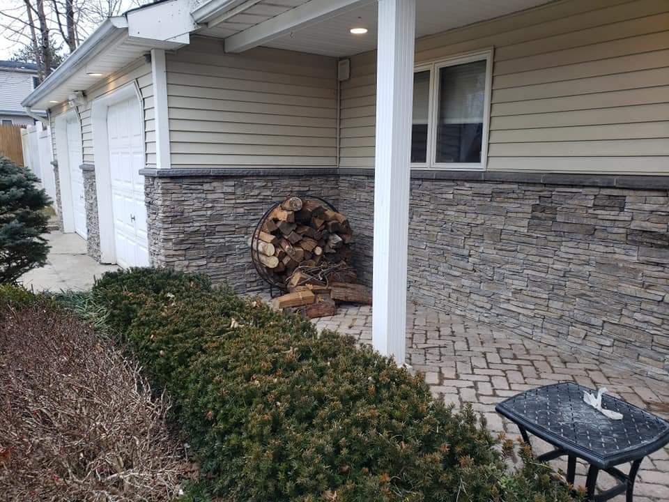 A pile of wood is sitting on the porch of a house.