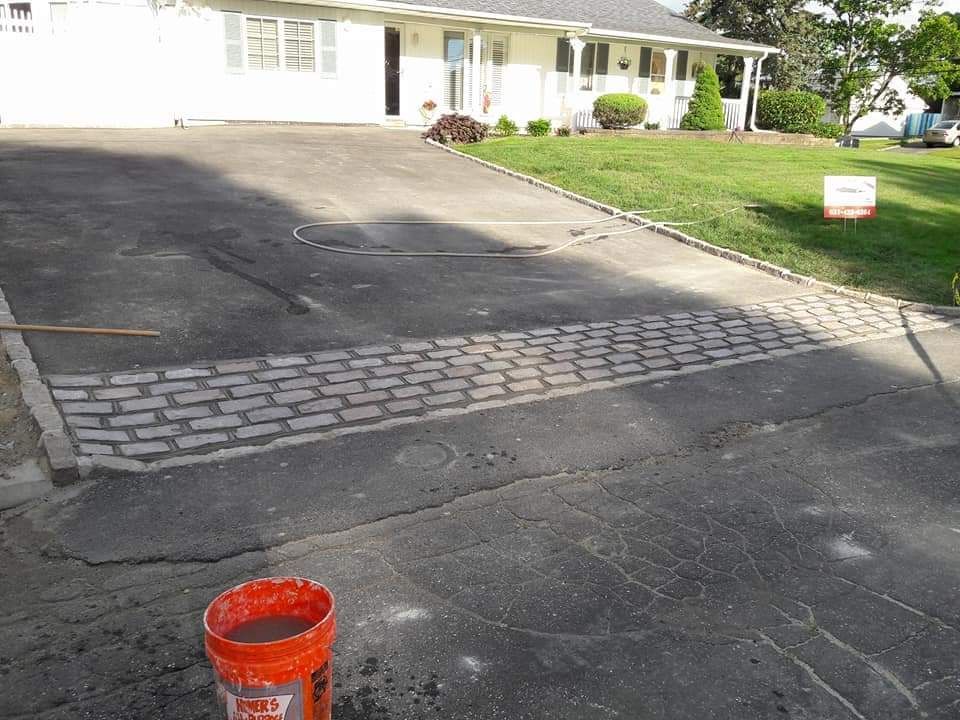An orange bucket is sitting on the side of a road in front of a house.