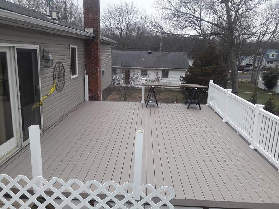 A large deck with a white fence and a table on it.