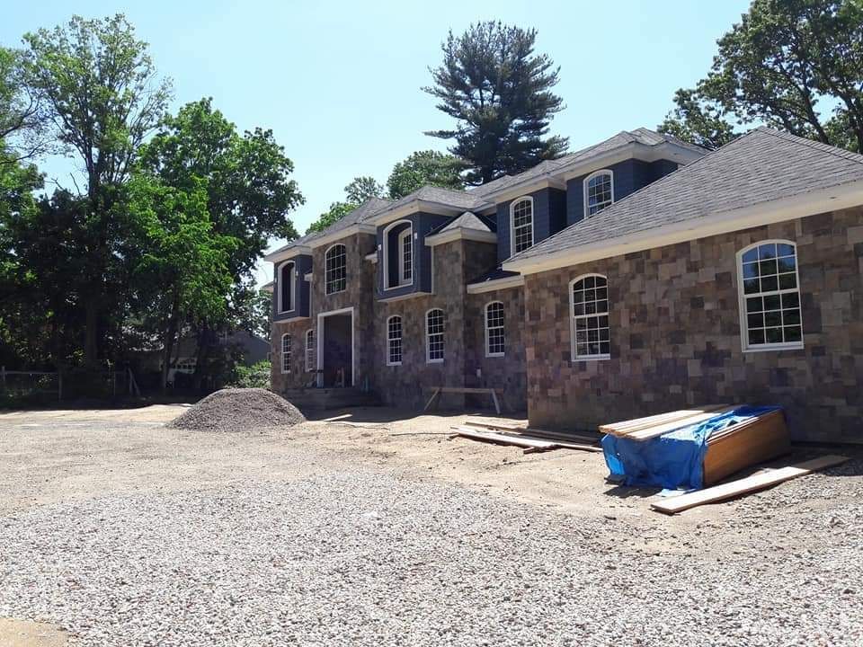 A large brick house is being built in a gravel lot