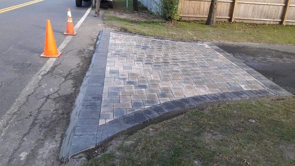 A brick walkway is being built on the side of the road.