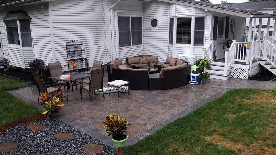 A patio with a couch , table and chairs in front of a house.