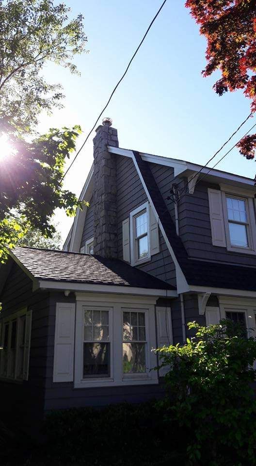 A gray house with white shutters and a black roof