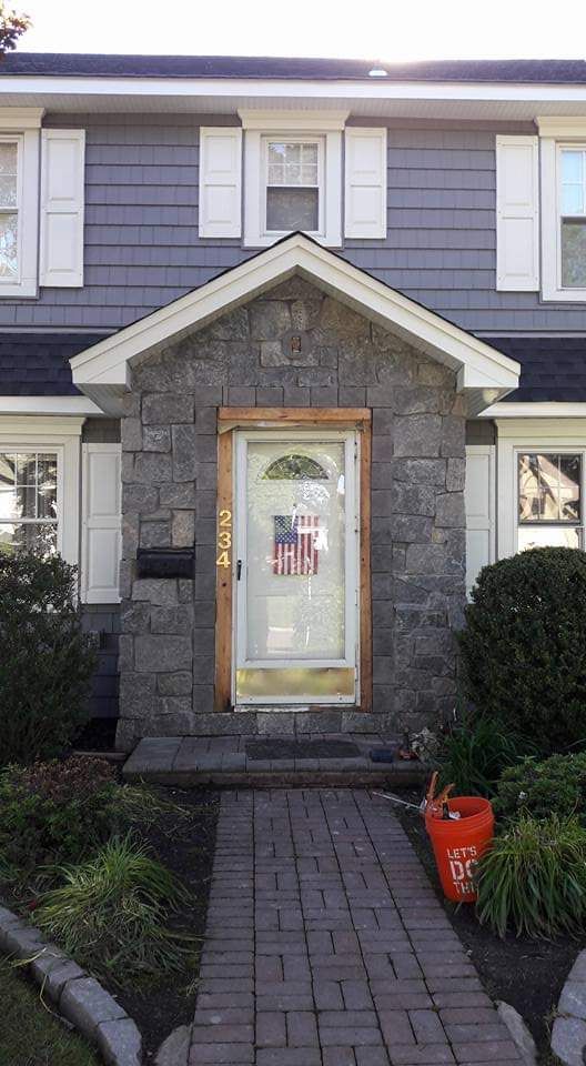 A house with a stone front door and a brick walkway leading to it.