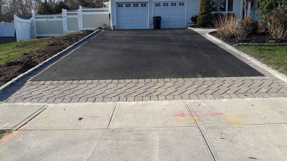 A driveway leading to a house with a white fence