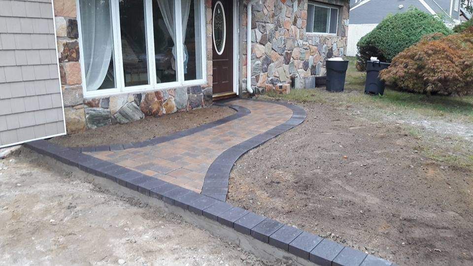 A stone house with a walkway leading to the front door.