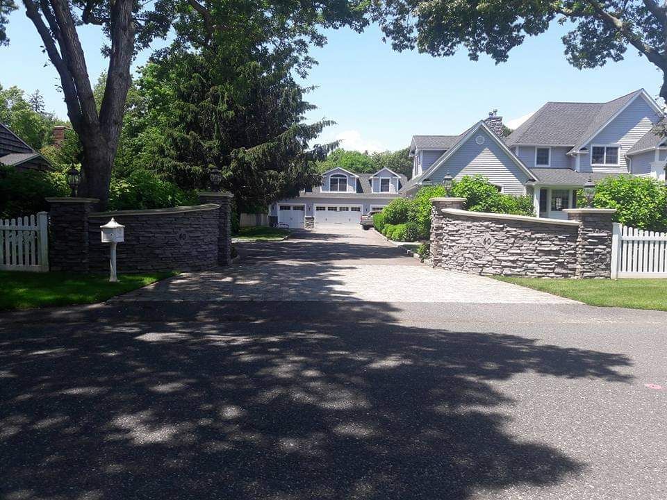 A driveway leading to a house with a white picket fence