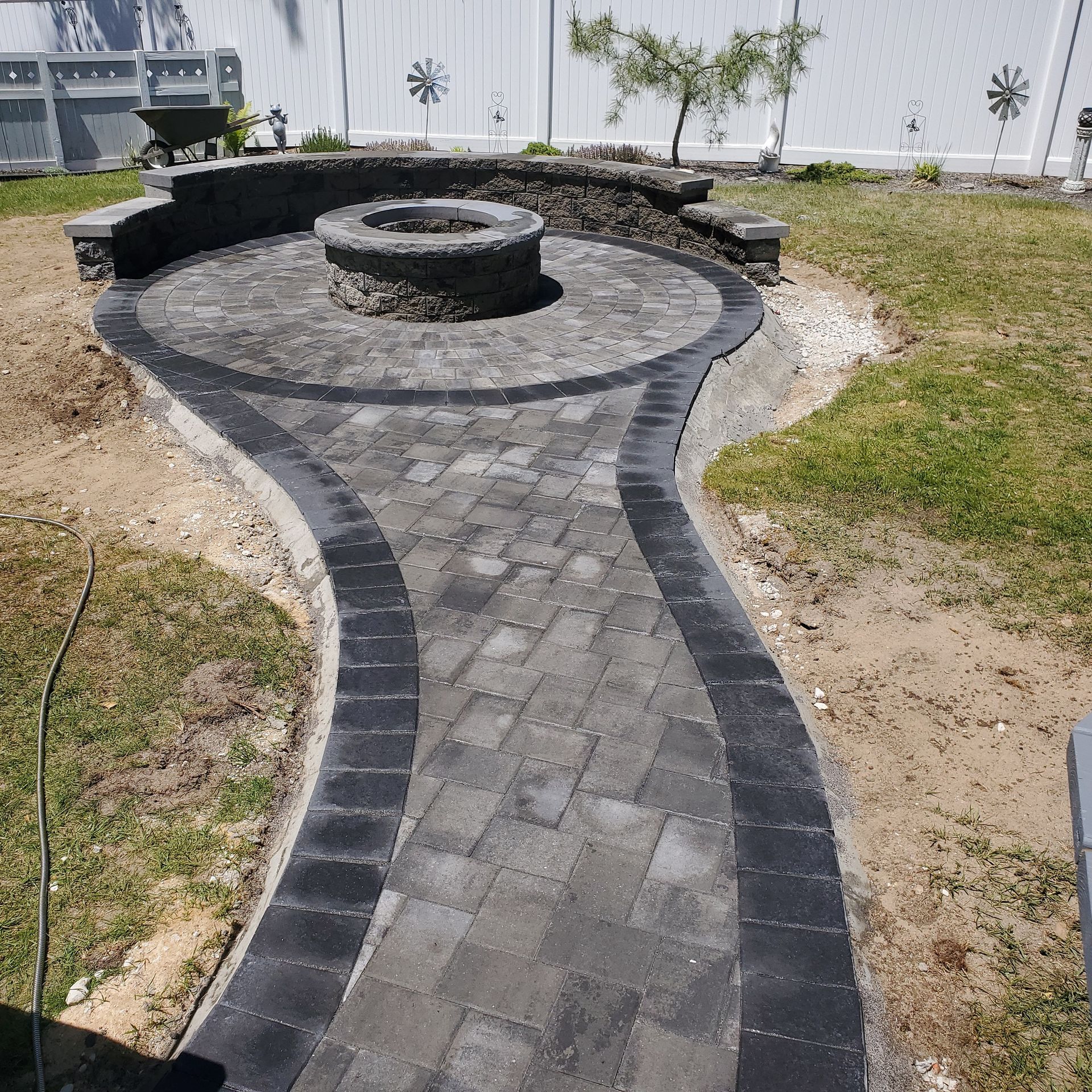 A brick walkway with a fire pit in the middle