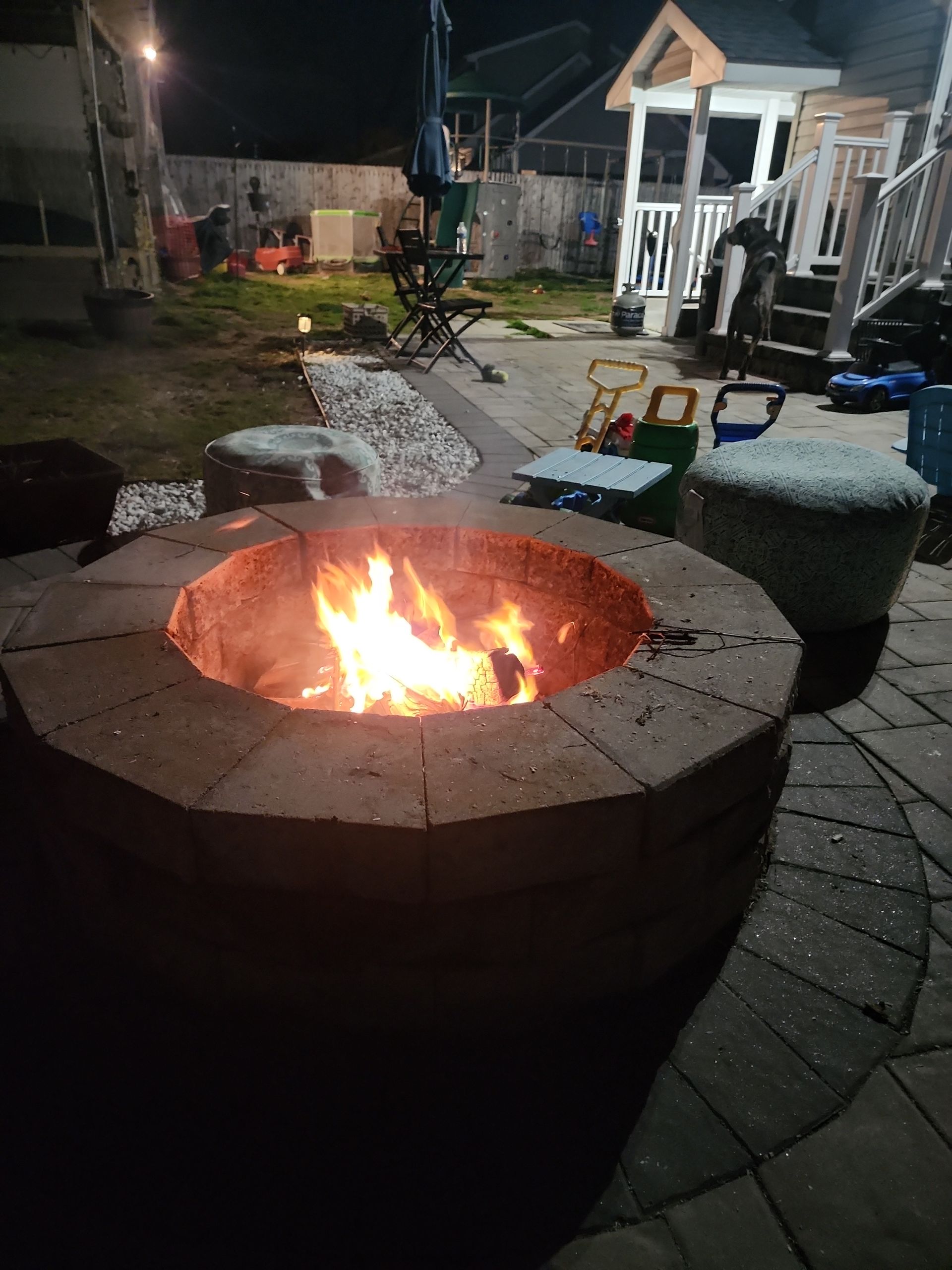 A fire pit is lit up in a backyard at night.