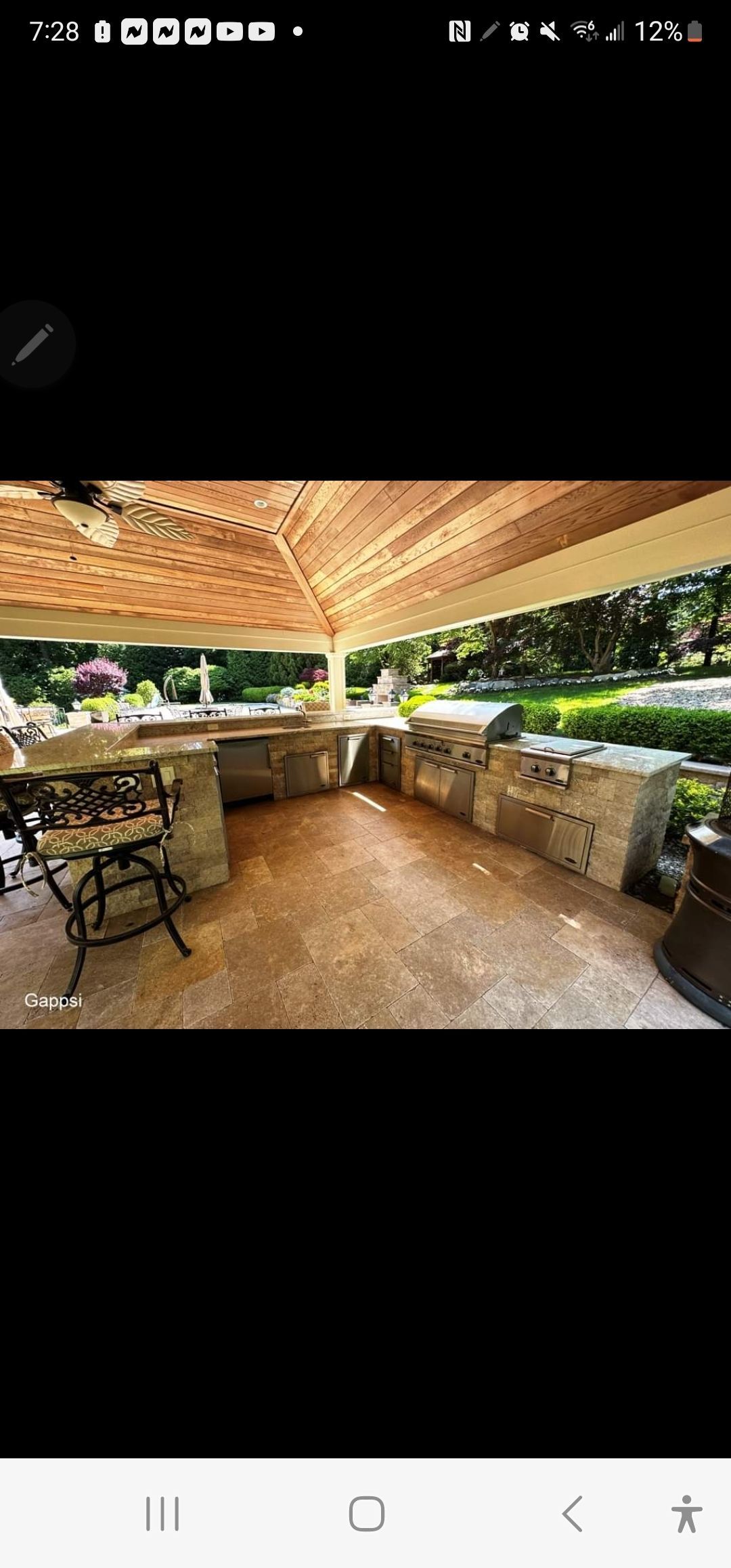 A large outdoor kitchen with a table and chairs under a pergola.