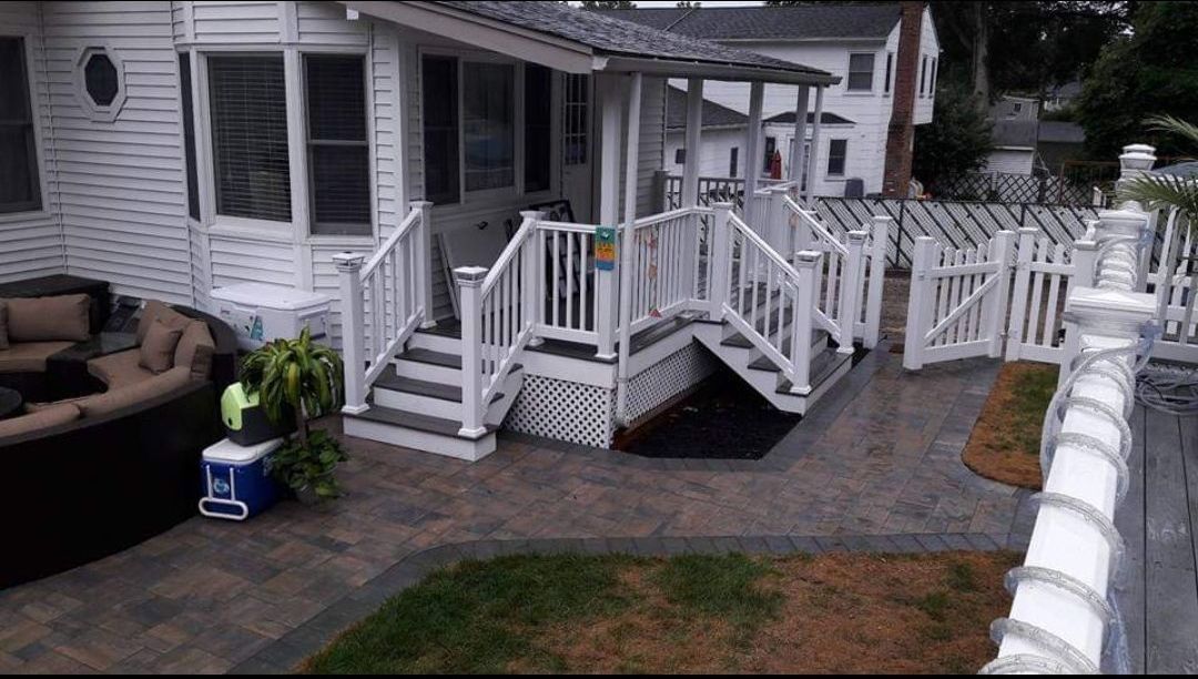 A white house with a large deck and stairs