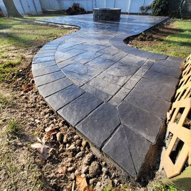 Concrete patio with a dark stone pattern, curved walkway, and fire pit.