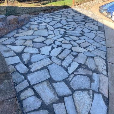 A stone walkway is being built next to a pool.