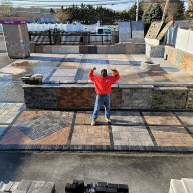 A man in a red sweatshirt is standing in front of a display of bricks.