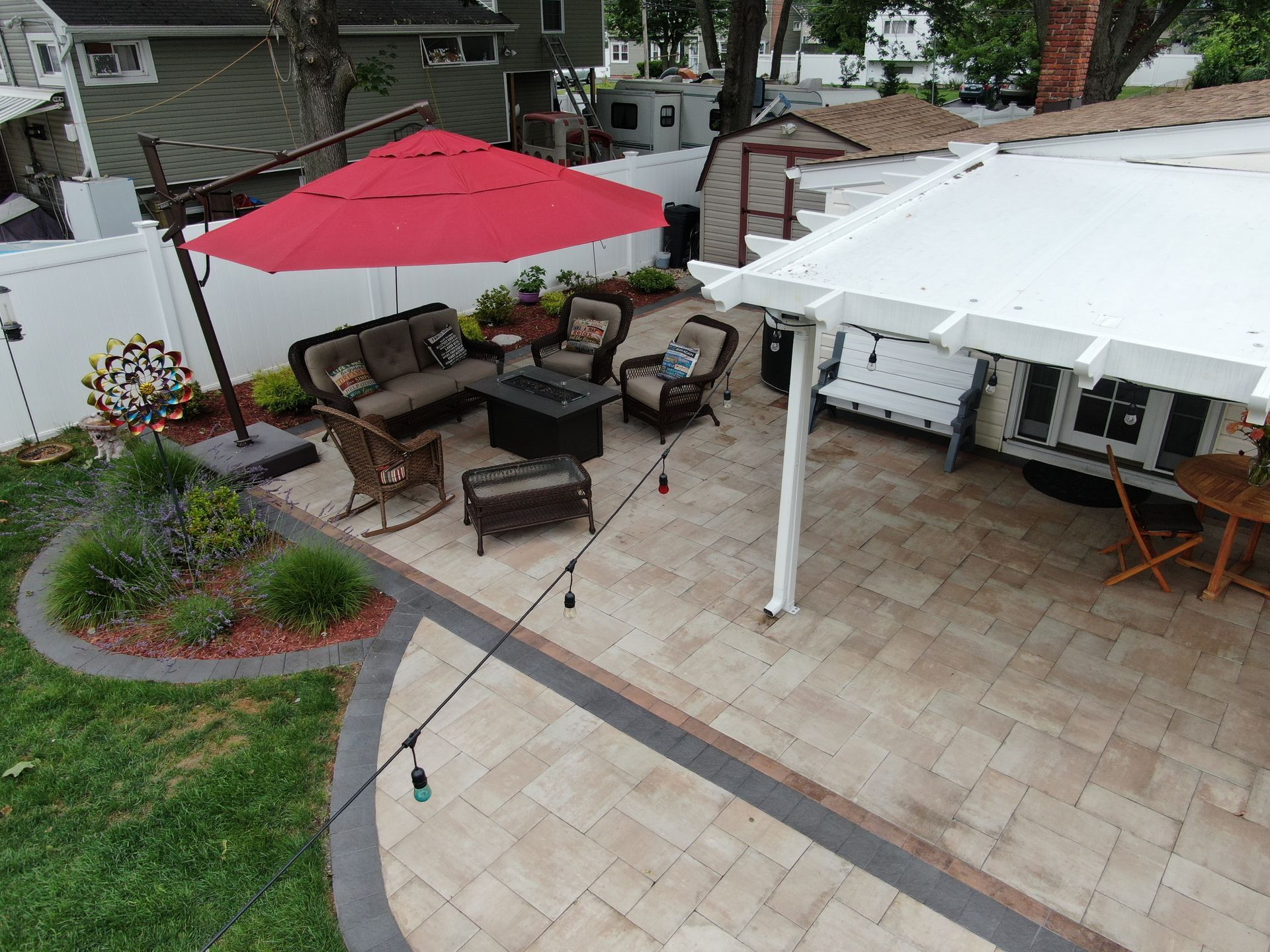 An aerial view of a patio with a red umbrella and a pergola.