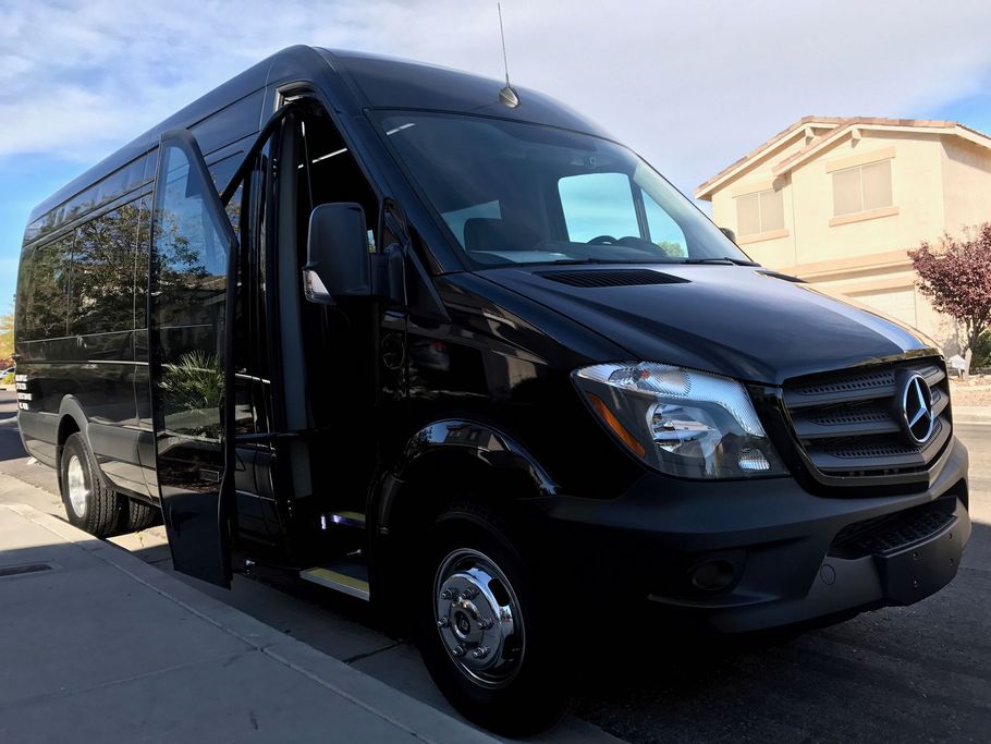 Black Mercedes-Benz Sprinter van, side door open, parked on a street in front of a house.
