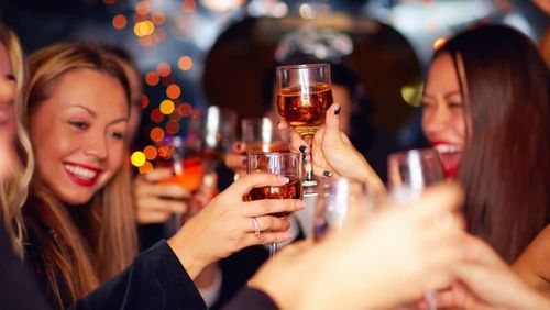 People toasting champagne glasses at a dimly lit party.