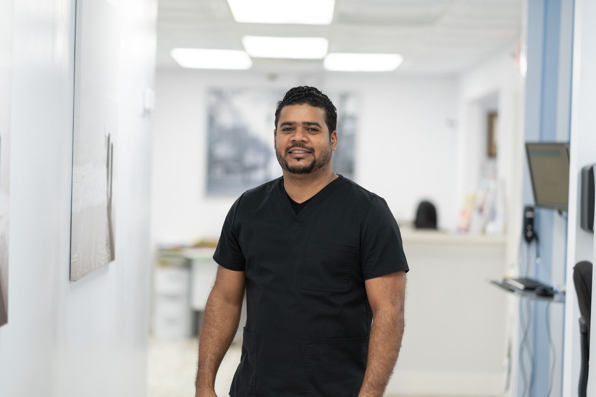 A man in a black shirt is standing in a hallway in a hospital.