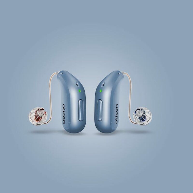 A pair of blue hearing aids on a blue background.