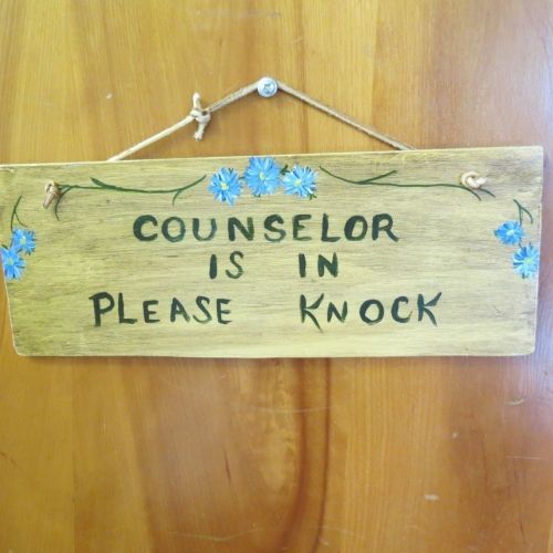 A wooden sign that says counselor is in please knock