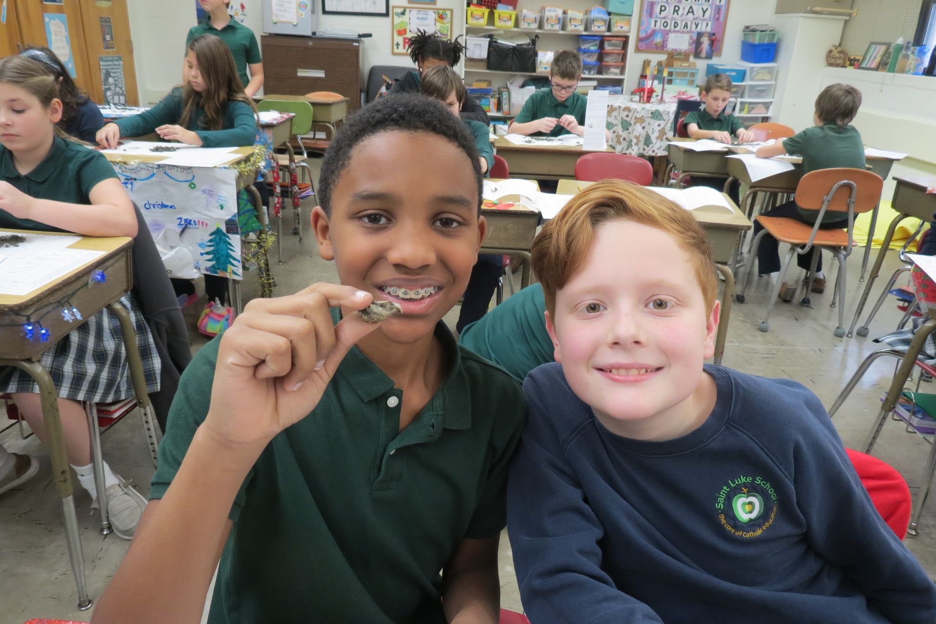 Two boys are standing in front of a display board that says ' crystals ' on it