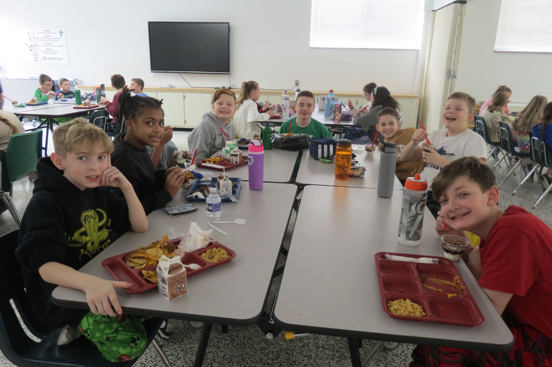 A group of young girls are sitting at a table eating lunch