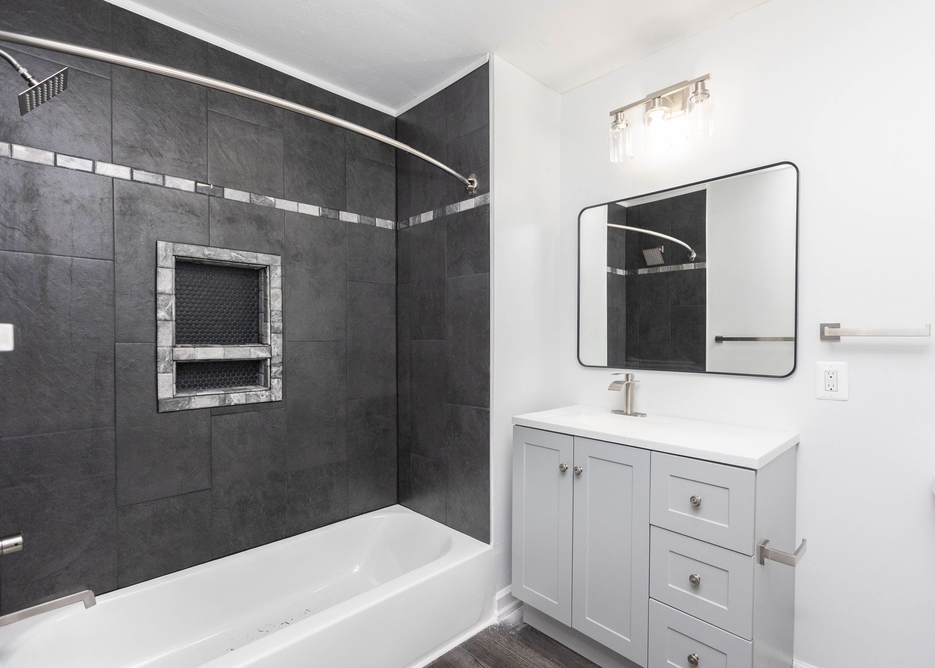 a bathroom with a bathtub , sink , mirror and shower .