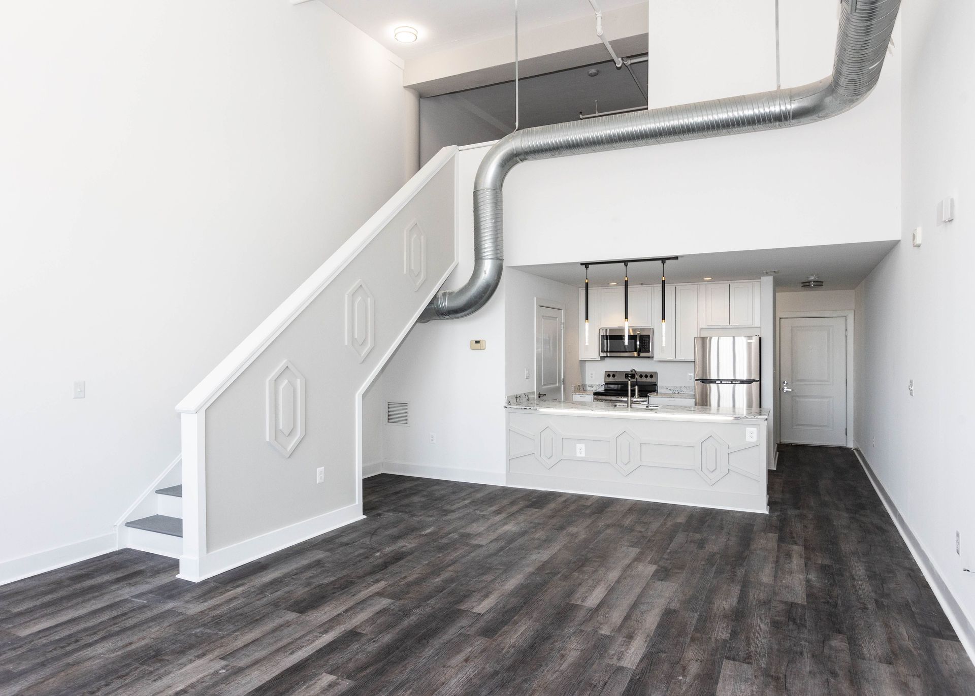 a living room with stairs leading up to the second floor and a kitchen .