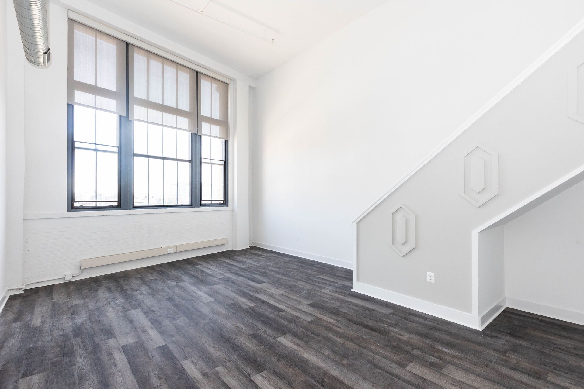 an empty living room with stairs and a large window .