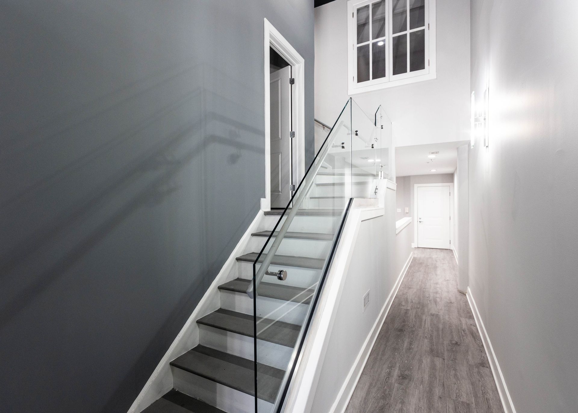 a hallway with stairs and a glass railing in a house .