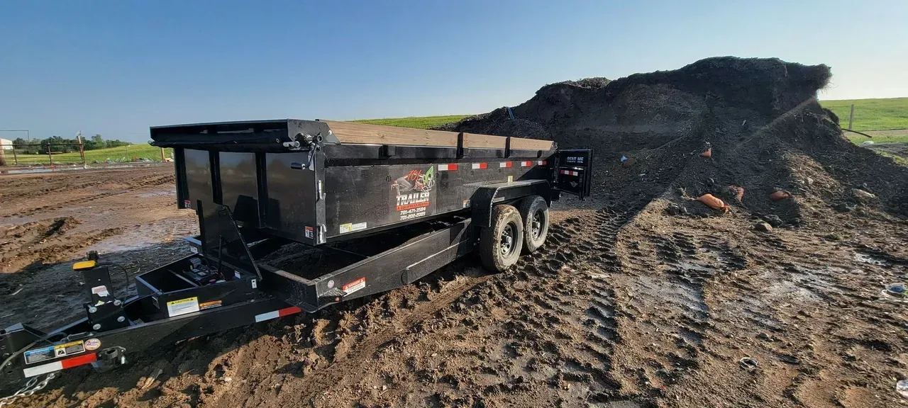 A dump truck is pulling a trailer full of dirt.