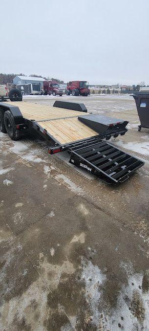 A trailer with a ramp attached to it is parked in a parking lot.