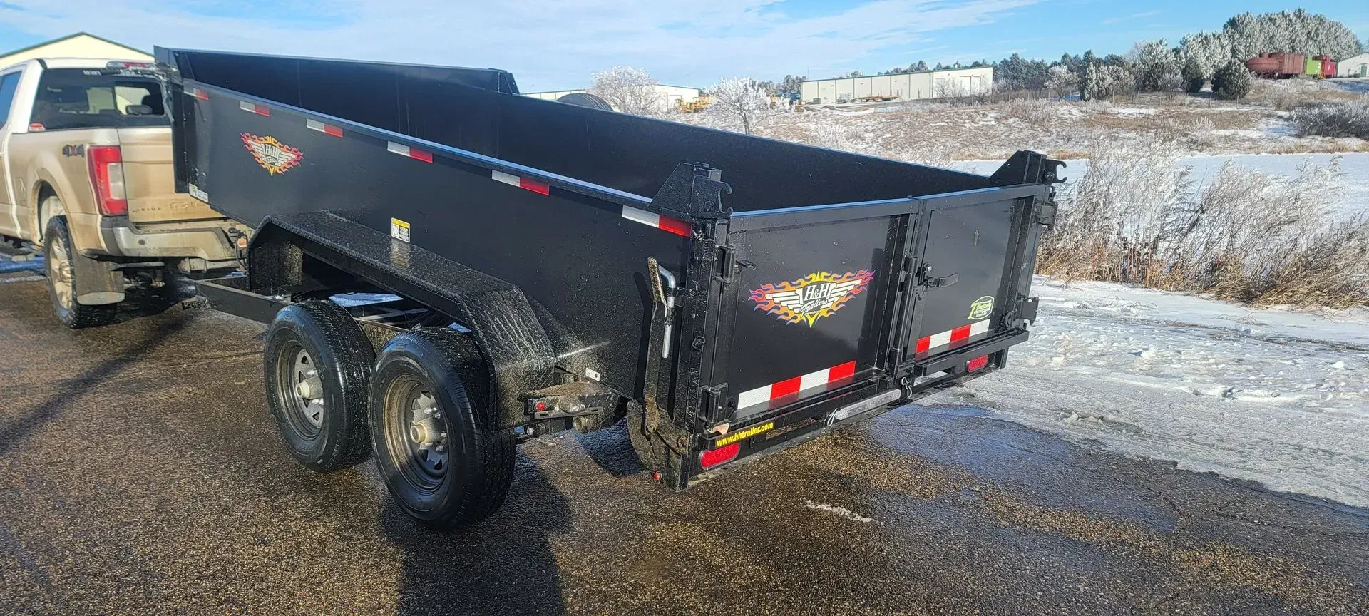 A dump truck with a trailer attached to it is parked on the side of the road.