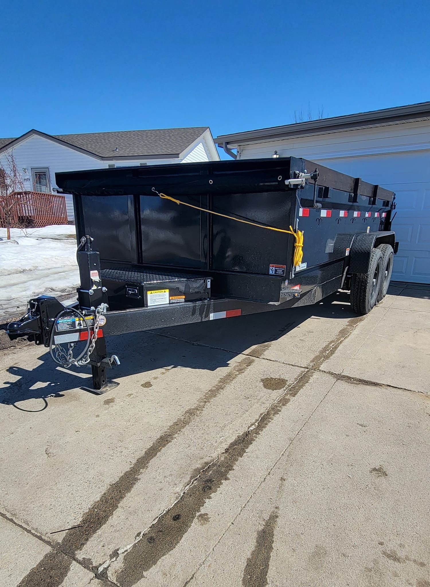 A dumpster trailer is parked in a driveway in front of a house.