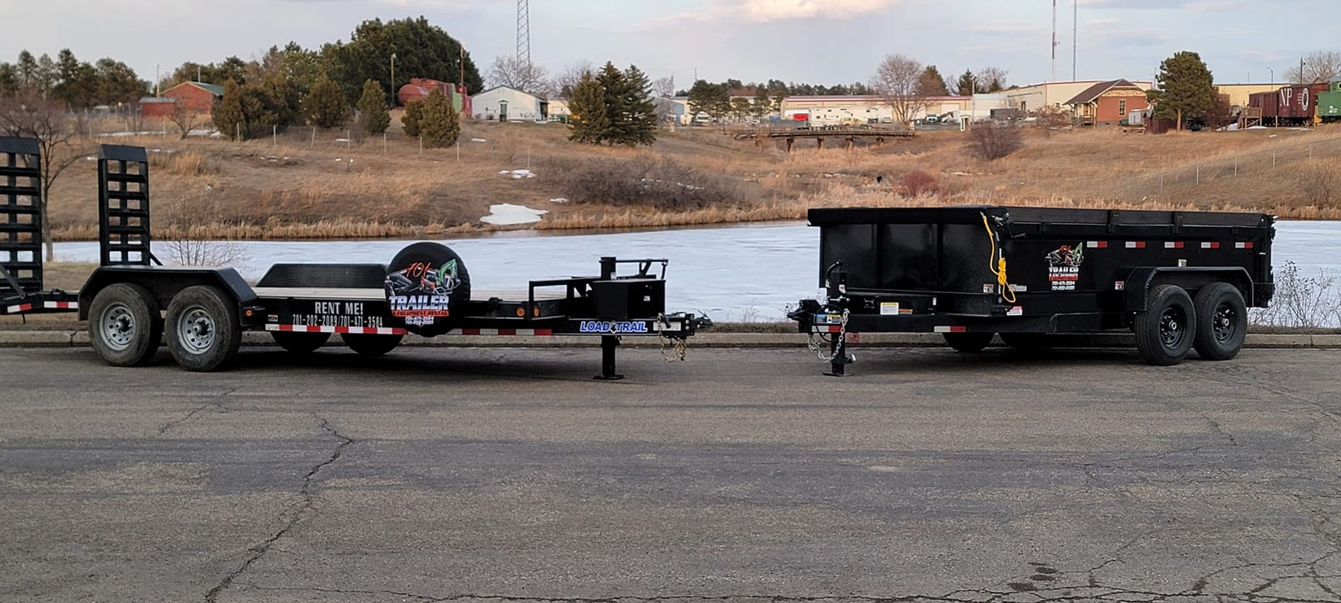 Two trailers are parked next to each other on the side of the road.