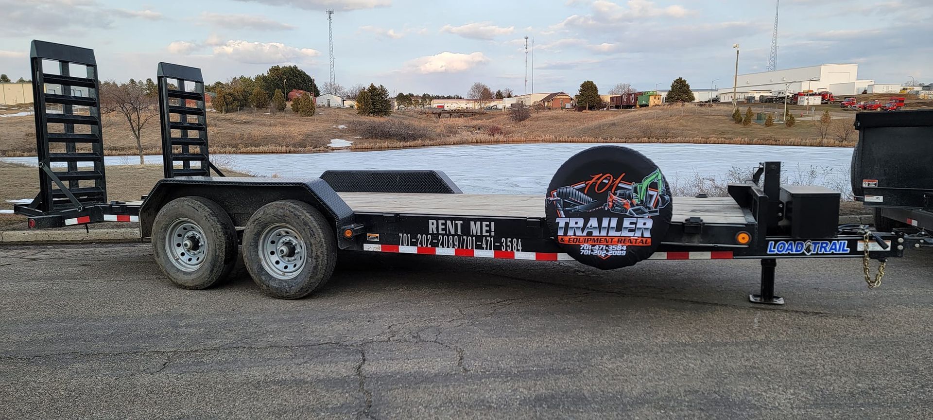 A trailer is parked on the side of the road next to a body of water.