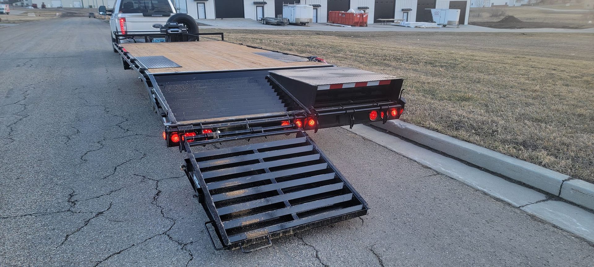 A trailer with a ramp attached to it is parked on the side of the road.