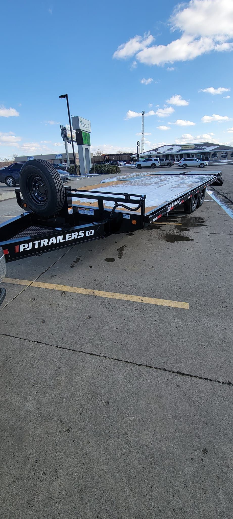 A flatbed trailer is parked in a parking lot.