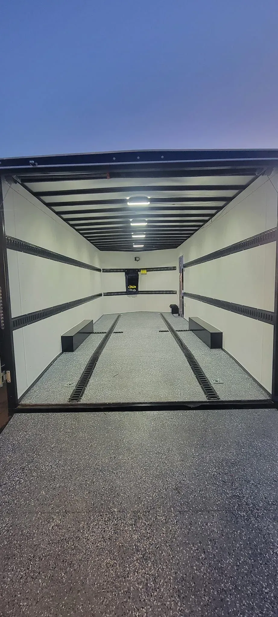 The inside of a trailer with a concrete floor and a blue sky in the background.