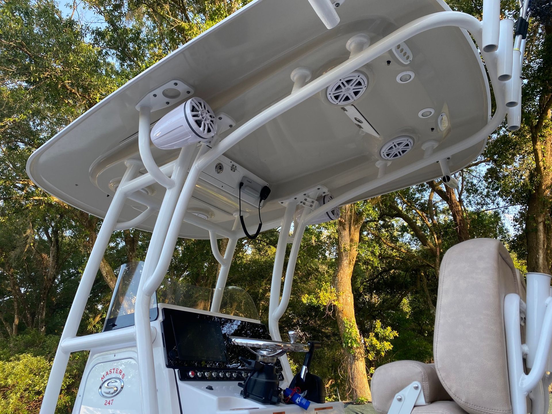 A white boat with a roof that has speakers on it.