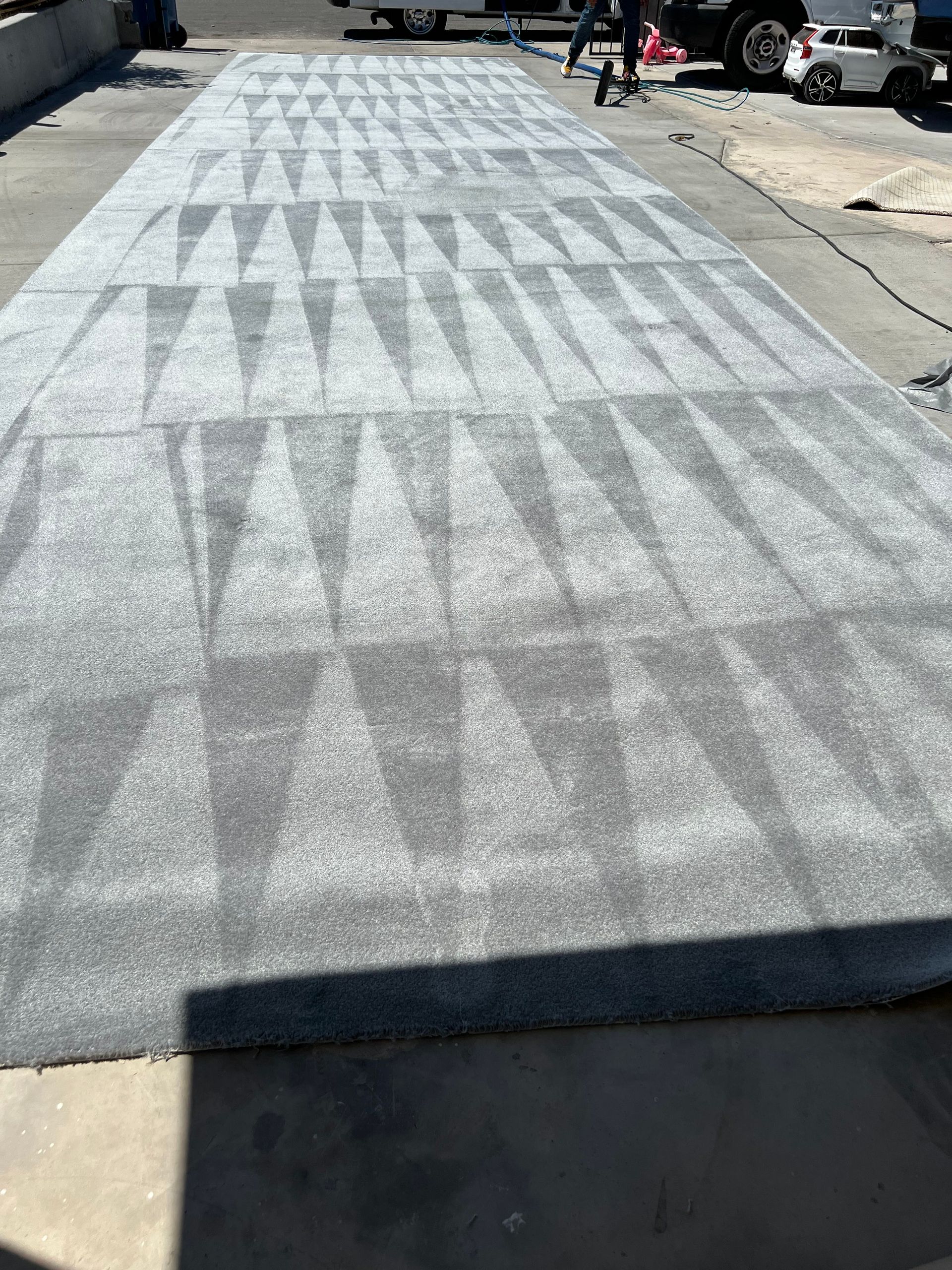 Gray pavement with a geometric pattern; person working on the pattern.