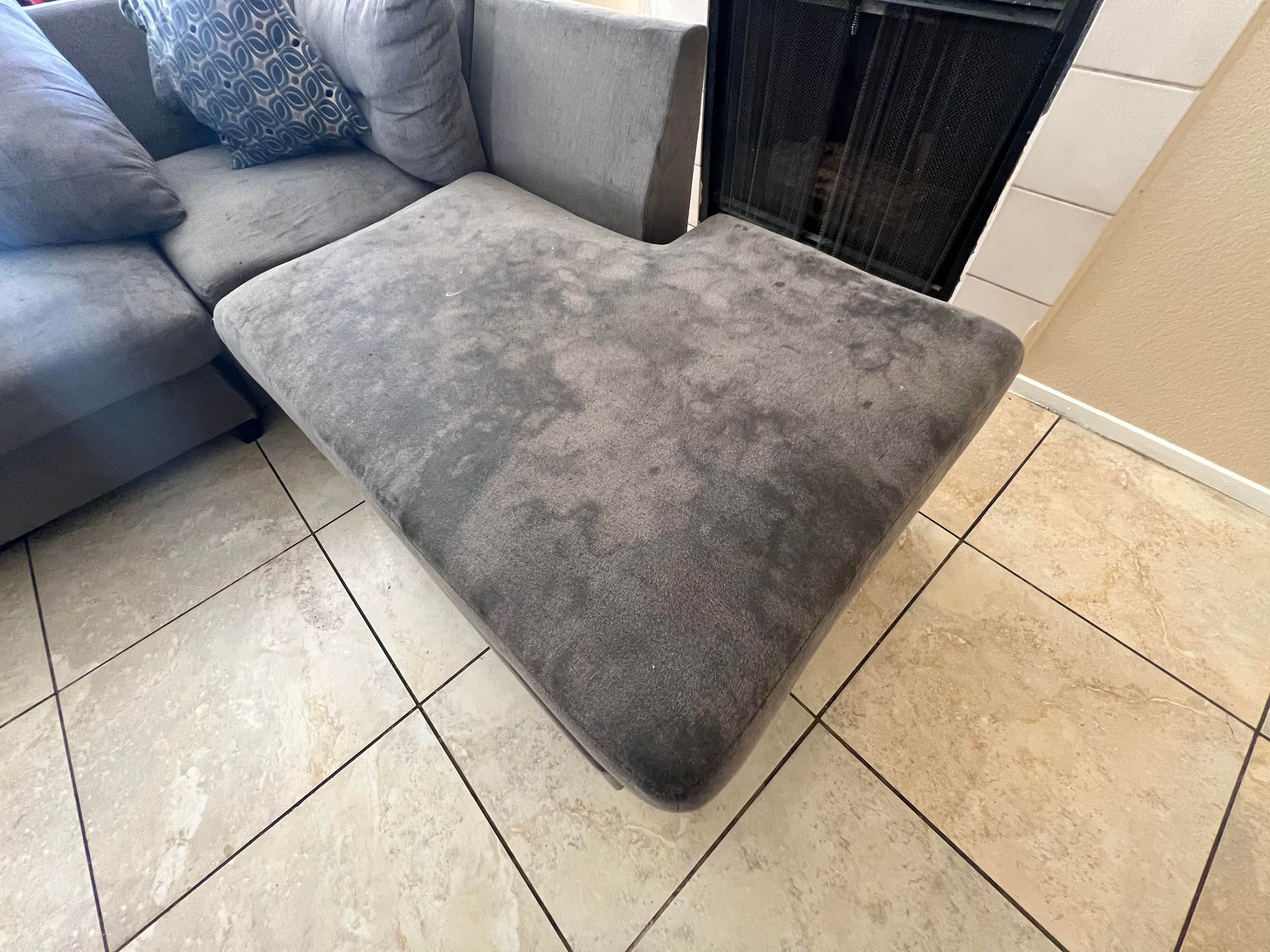 Gray sectional sofa with a chaise lounge on a tiled floor.