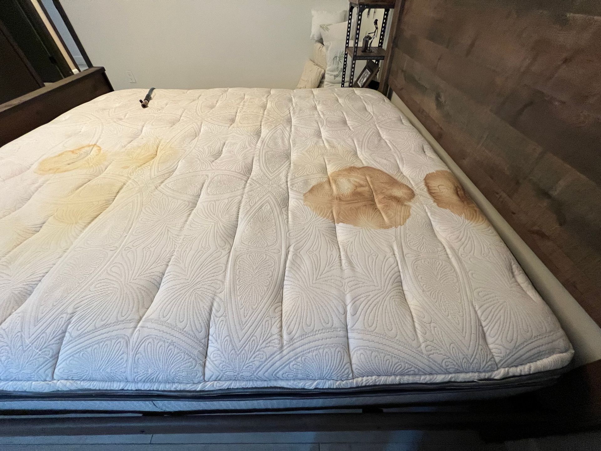 A mattress with multiple large, discolored stains; likely urine.
