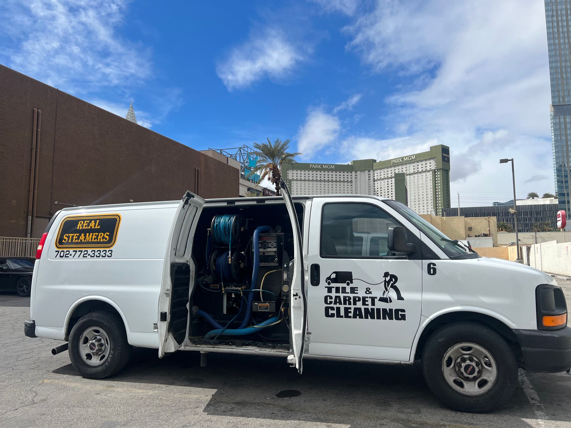 White van for tile and carpet cleaning parked outdoors with doors open, equipment visible.