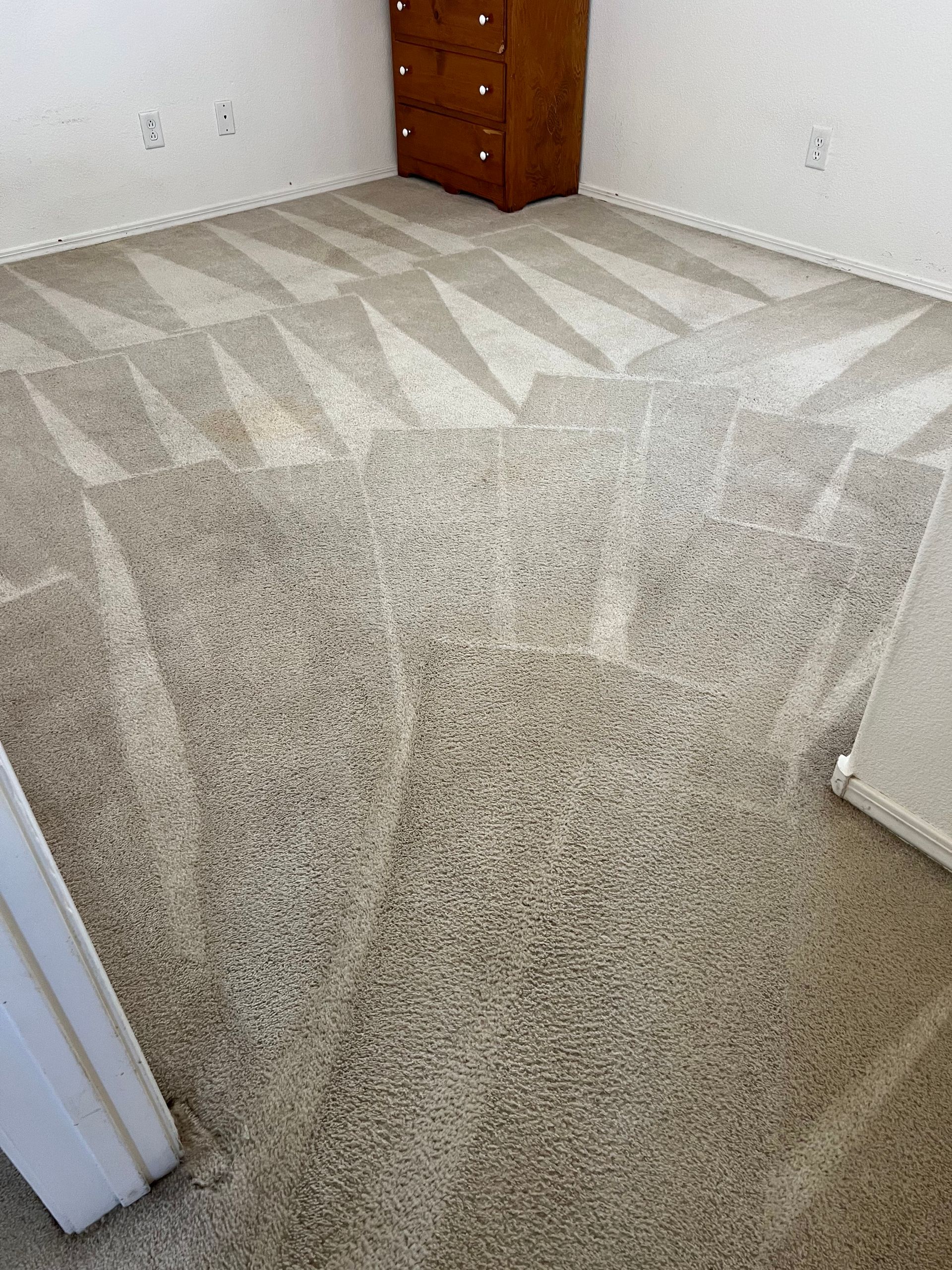 Beige carpet with geometric patterns in a room, a dresser in the background.