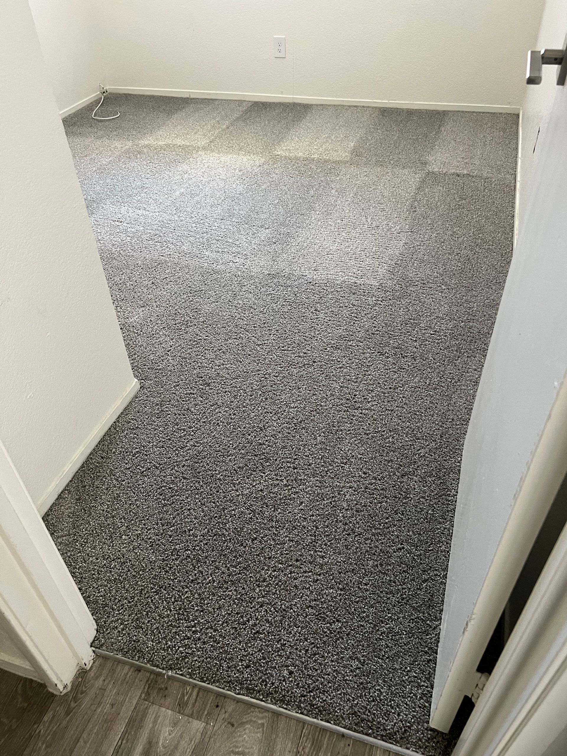 Room with epoxy-coated floor in shades of gray, white, and black. Doorways and white walls are visible.